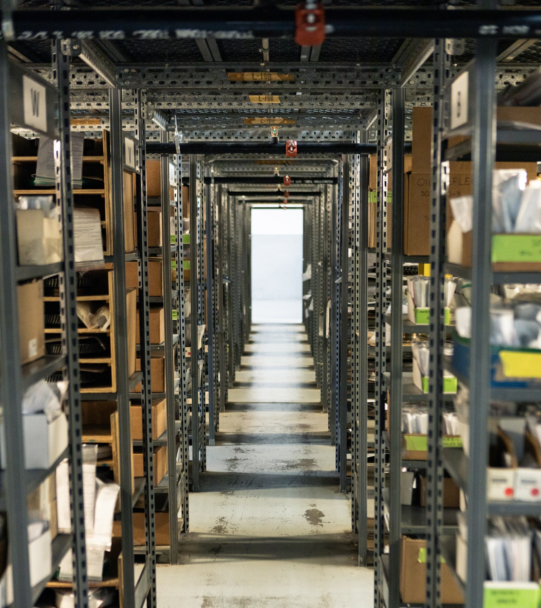 Long warehouse aisle with shelves filled with aircraft parts and documents