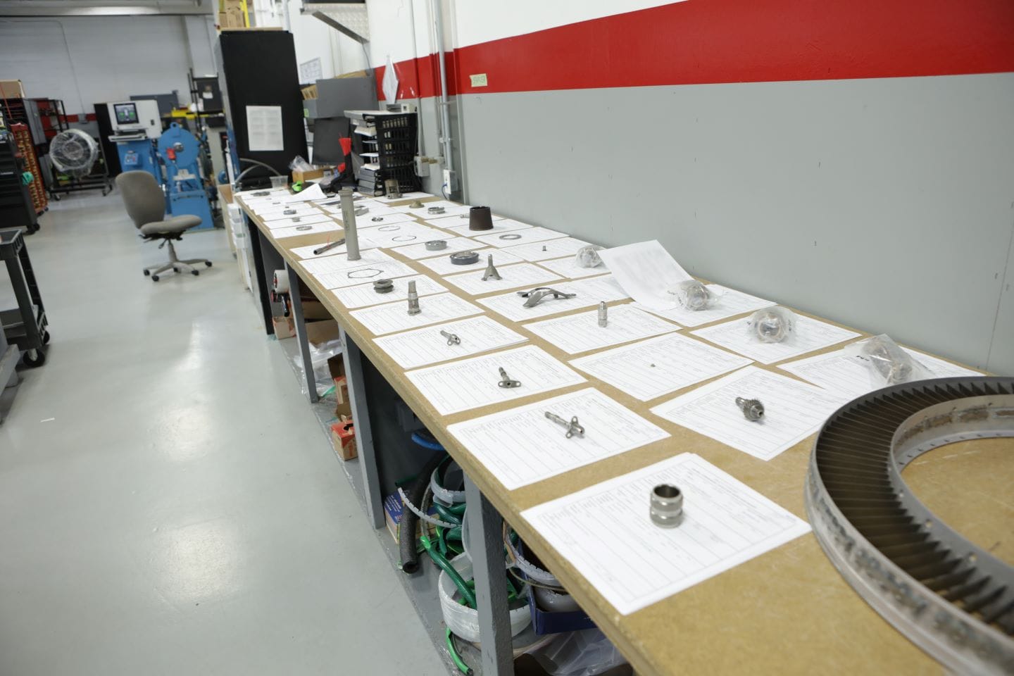 Workbench lined with organized aircraft engine parts and paperwork