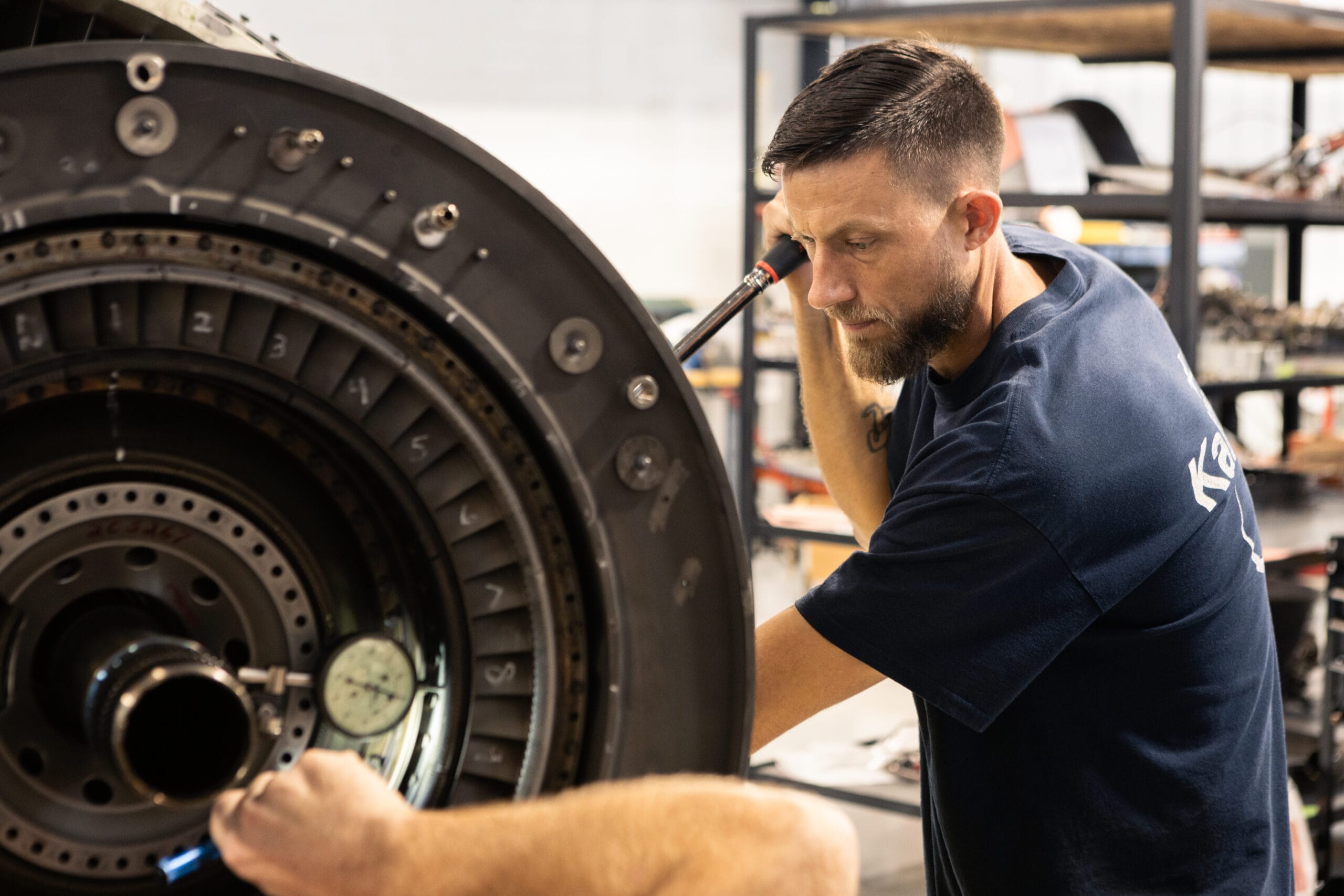 Technician working on a large aircraft engine component with tools