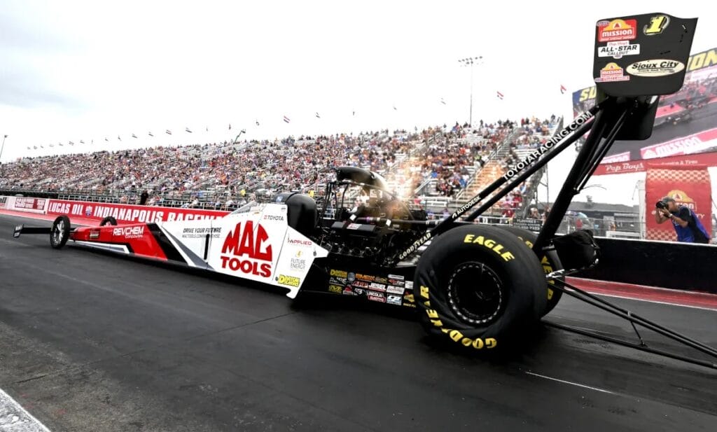 Drag racing car with Mac Tools branding at a racetrack with a crowd in the background