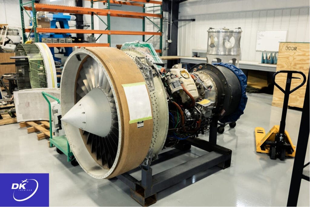 Aircraft engine prototype mounted on a stand in a maintenance facility, showcasing early-stage development and testing processes. The exposed components and surrounding tools highlight the transition from design to operational readiness.