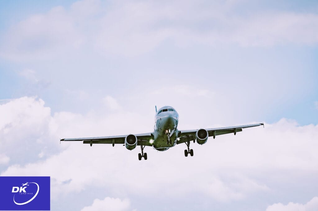 Commercial aircraft approaching for landing against a cloudy sky, representing the critical role of certified turbine engines and rotable parts in safe and efficient flight operation. DK Turbines logo in the corner underscores their commitment to reliable aviation support and maintenance.